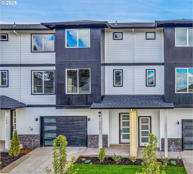 multi unit property featuring an attached garage, driveway, and stone siding