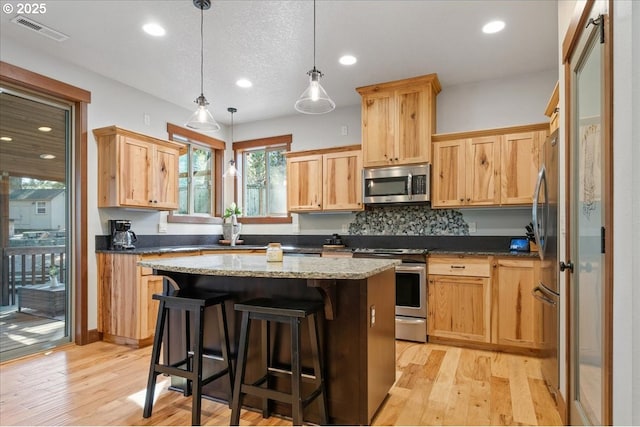 13135 SE Winston Rd, Damascus, OR 97089 - kitchen with visible vents, appliances with stainless steel finishes, a kitchen island, and light wood-type flooring