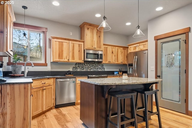 13135 SE Winston Rd, Damascus, OR 97089 - kitchen featuring a kitchen island, a kitchen bar, appliances with stainless steel finishes, a sink, and light wood finished floors