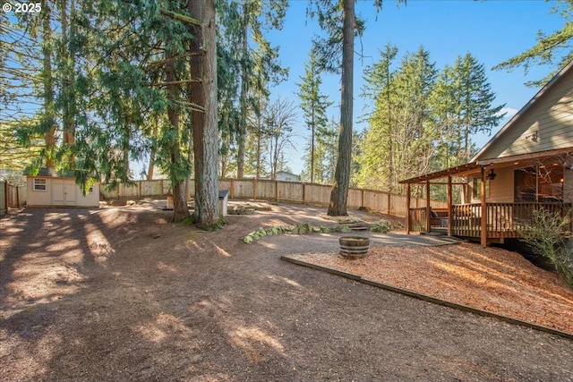 13135 SE Winston Rd, Damascus, OR 97089 - view of yard featuring a shed, a deck, a fenced backyard, an outdoor structure, and a fire pit