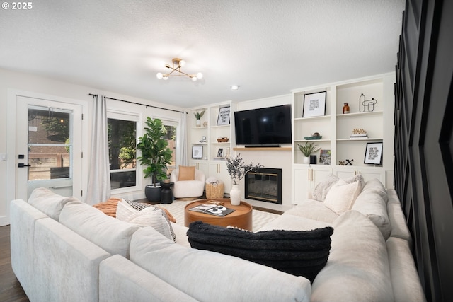 16223 SW 146th Ave, Portland, OR 97224 - living room with a fireplace with flush hearth, dark wood-style floors, a chandelier, built in shelves, and a textured ceiling