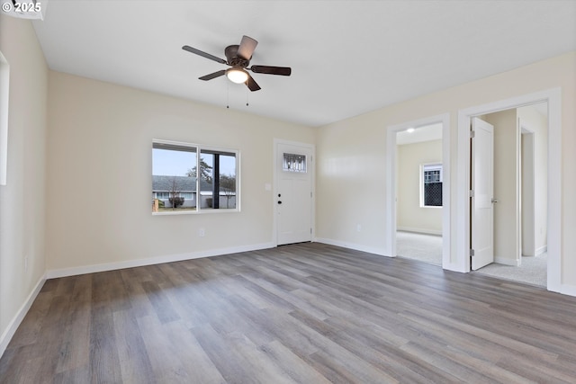 empty room with light wood-type flooring, a ceiling fan, and baseboards