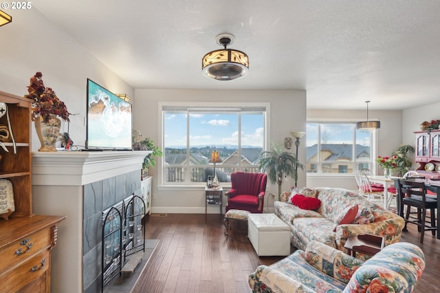 living room featuring a fireplace, a textured ceiling, baseboards, and hardwood / wood-style flooring