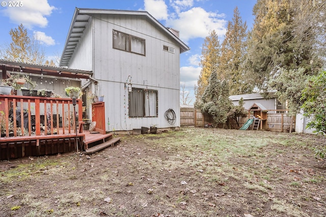 rear view of property with a playground and a deck