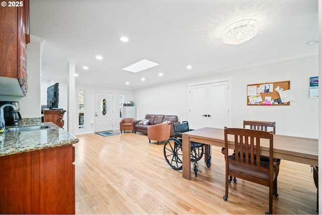 dining space with recessed lighting, light wood-style flooring, a skylight, and ornamental molding