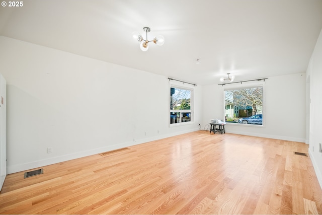 empty room with wood finished floors, visible vents, and baseboards