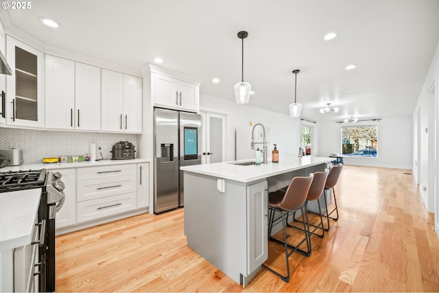 kitchen with light countertops, decorative backsplash, appliances with stainless steel finishes, white cabinetry, and a sink