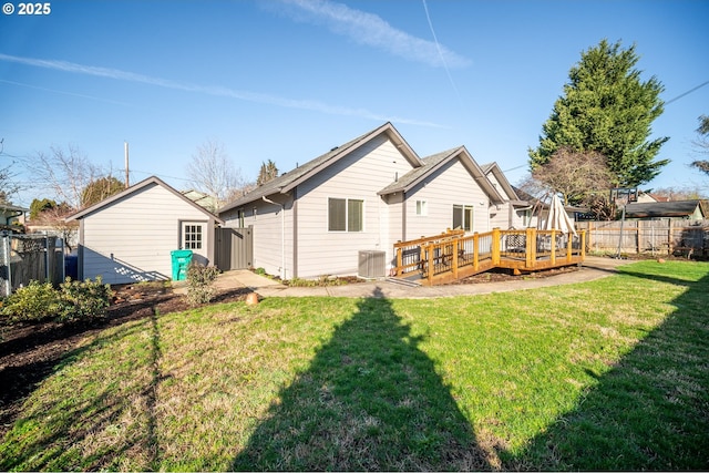 rear view of house with an outbuilding, a deck, a yard, and fence