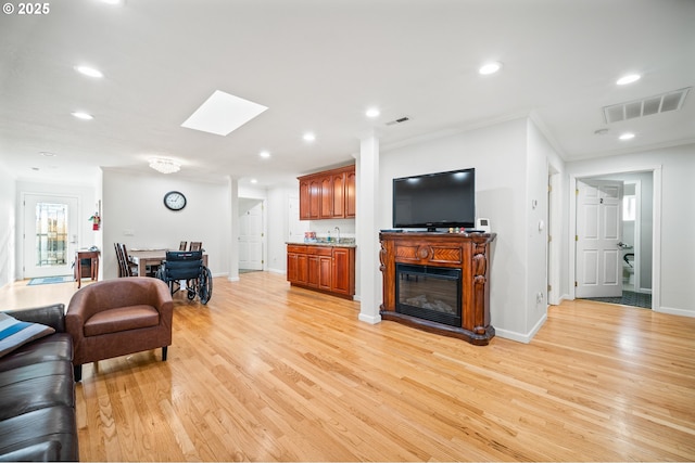 living room with light wood-type flooring, visible vents, recessed lighting, crown molding, and wet bar
