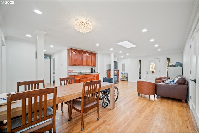 dining area featuring a skylight, light wood-type flooring, ornamental molding, and recessed lighting
