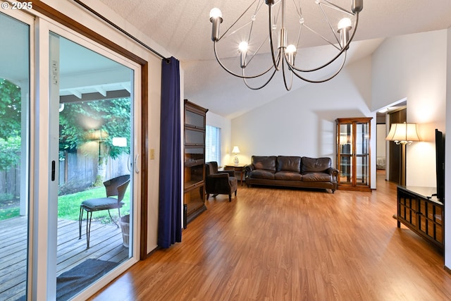 living area with vaulted ceiling, light wood-style floors, a chandelier, and a textured ceiling