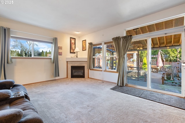 unfurnished living room with a healthy amount of sunlight, carpet floors, and a tile fireplace