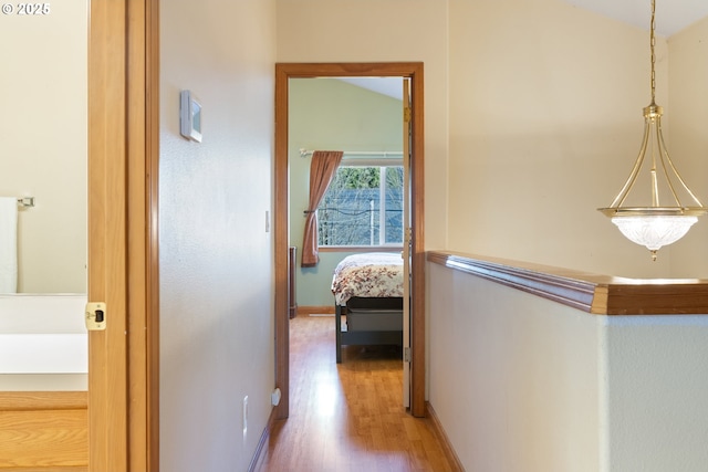 hallway with wood-type flooring and vaulted ceiling