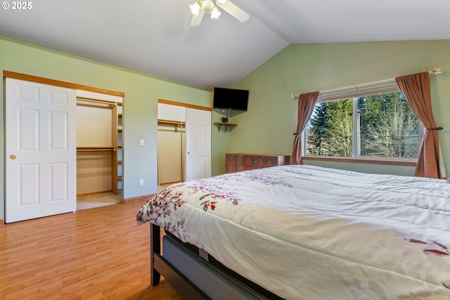 bedroom featuring ceiling fan, lofted ceiling, wood-type flooring, and two closets