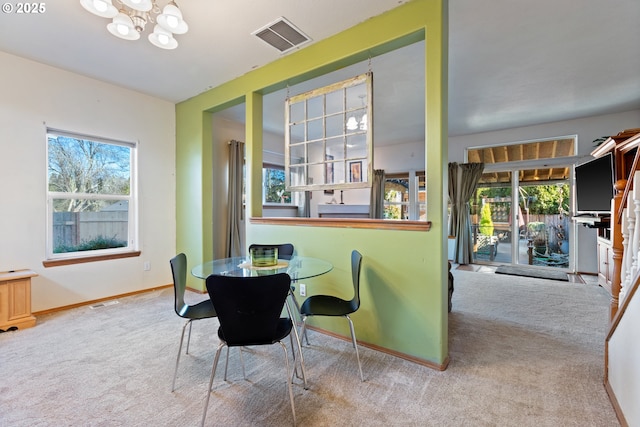 carpeted dining room with a chandelier and a wealth of natural light