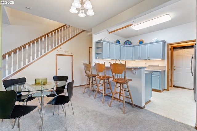 kitchen with a breakfast bar, light colored carpet, a notable chandelier, kitchen peninsula, and blue cabinetry