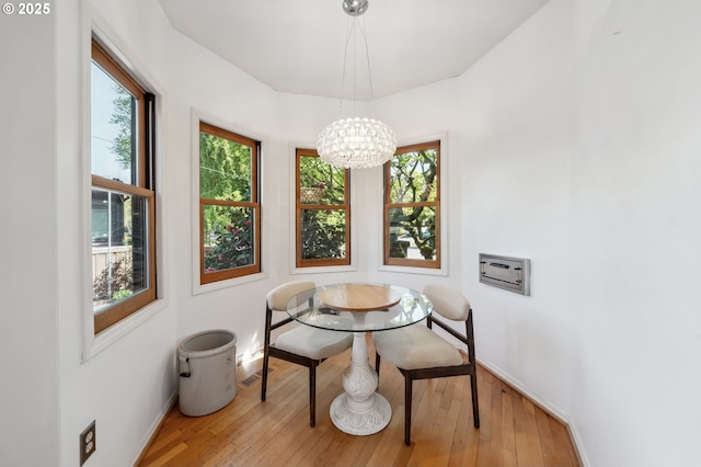 dining space with an inviting chandelier, baseboards, wood-type flooring, and a wealth of natural light