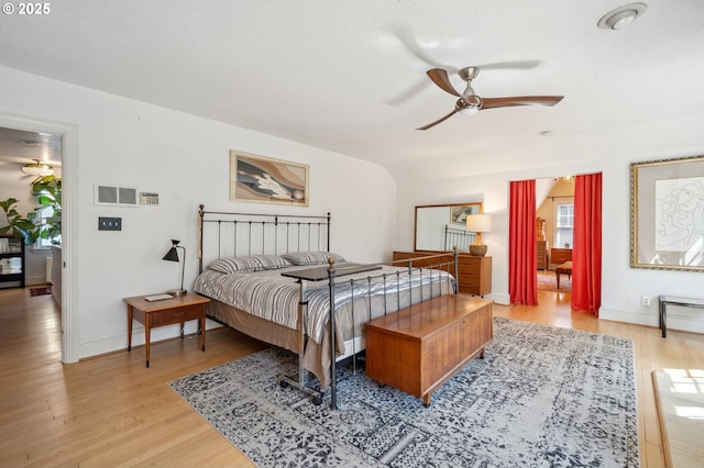 bedroom featuring baseboards, visible vents, vaulted ceiling, and light wood-type flooring