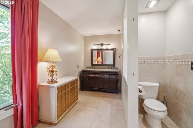 bathroom featuring tile patterned flooring, vanity, toilet, tile walls, and visible vents