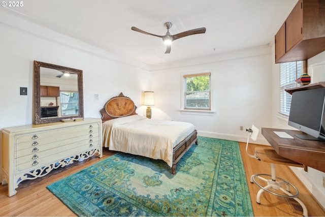 bedroom featuring baseboards, a ceiling fan, crown molding, and wood finished floors