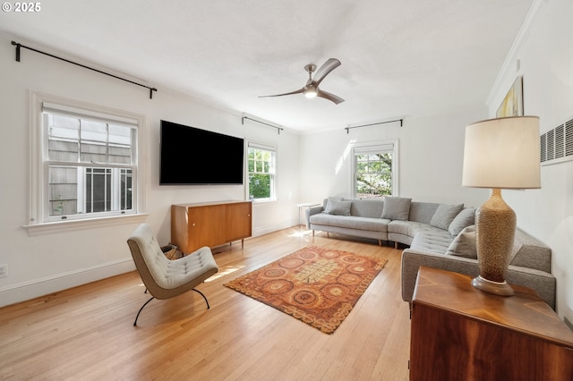 living area with crown molding, a ceiling fan, and wood finished floors