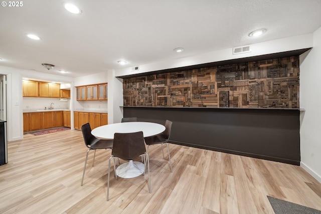 dining space featuring visible vents, baseboards, indoor wet bar, recessed lighting, and light wood finished floors