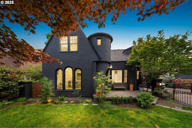 view of front of house with fence, a patio, stucco siding, and a front lawn