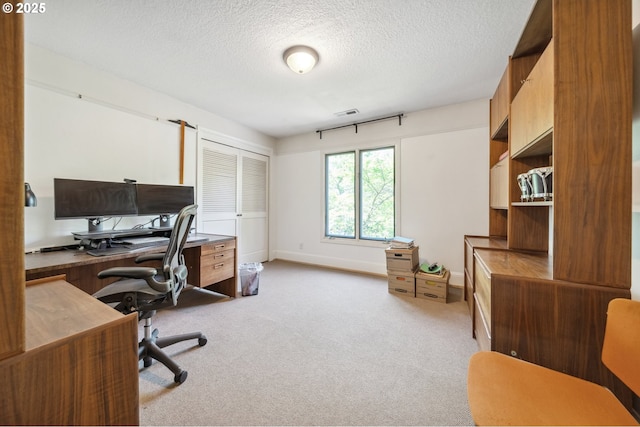 home office with baseboards, a textured ceiling, and light colored carpet
