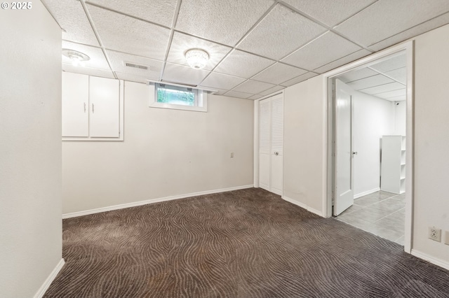 below grade area featuring visible vents, carpet, a paneled ceiling, and baseboards