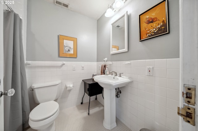 full bath featuring wainscoting, tile patterned flooring, toilet, tile walls, and visible vents