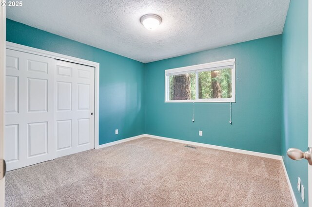 4718 SW Miles Ct, Portland, OR 97219 - unfurnished bedroom with carpet flooring, a textured ceiling, baseboards, and a closet