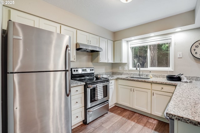 4718 SW Miles Ct, Portland, OR 97219 - kitchen featuring stainless steel appliances, under cabinet range hood, a sink, light wood-type flooring, and white cabinets