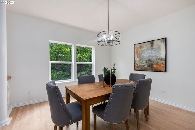 15530 SW Brighton Ct, Beaverton, OR 97007 - dining area with a chandelier, light wood-style floors, and baseboards