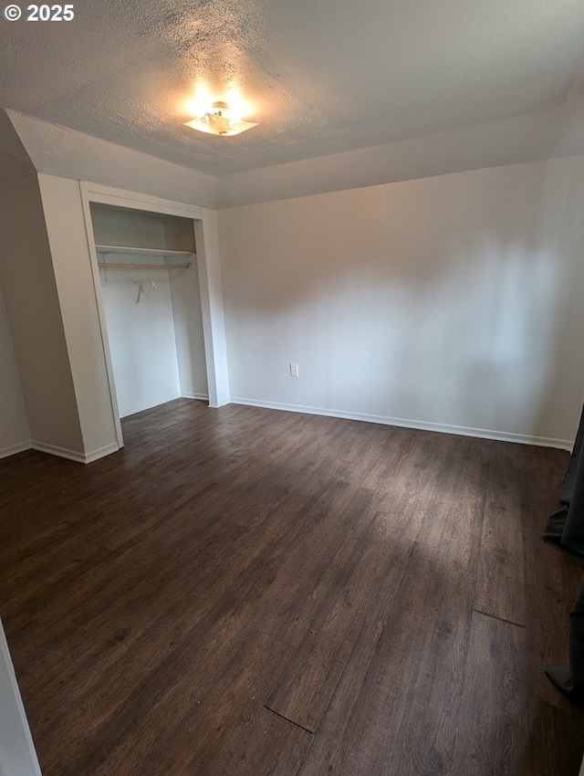 unfurnished bedroom with dark wood-style flooring, baseboards, a closet, and a textured ceiling