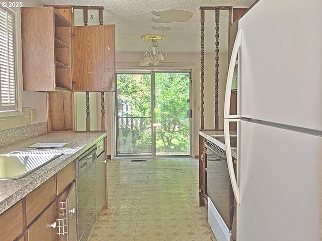 1367 NW Riverview Ave, Gresham, OR 97030 - kitchen featuring freestanding refrigerator, open shelves, a chandelier, healthy amount of natural light, and a textured ceiling