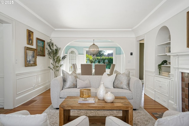 460 Bush St SE, Salem, OR 97302 - living area with built in shelves, a decorative wall, a chandelier, wainscoting, and wood finished floors