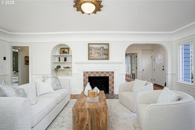 460 Bush St SE, Salem, OR 97302 - living room featuring arched walkways, a tile fireplace, built in features, and wood finished floors