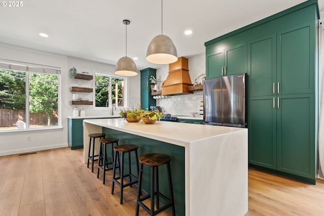 kitchen with freestanding refrigerator, open shelves, custom exhaust hood, and green cabinets