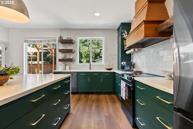 kitchen featuring open shelves, light countertops, premium range hood, green cabinetry, and stainless steel appliances