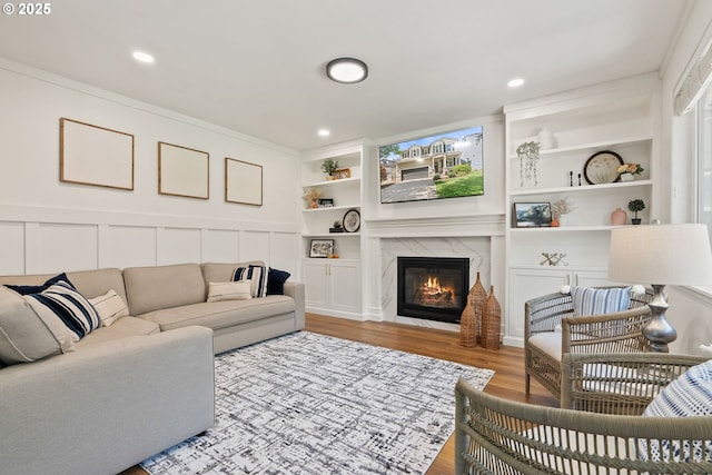 living area with recessed lighting, built in features, wood finished floors, and a fireplace