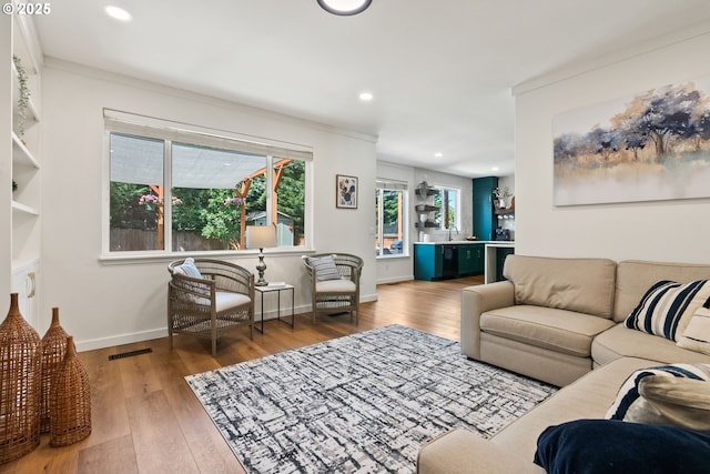 living area featuring recessed lighting, ornamental molding, baseboards, and wood finished floors