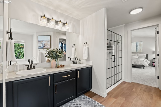 bathroom with a stall shower, a sink, and wood finished floors
