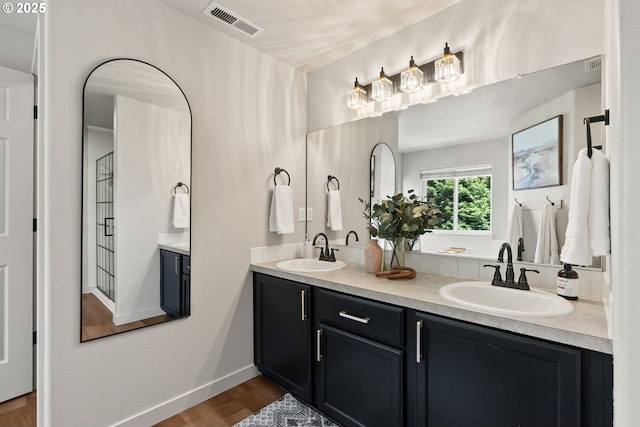 full bath featuring visible vents, a sink, wood finished floors, and double vanity