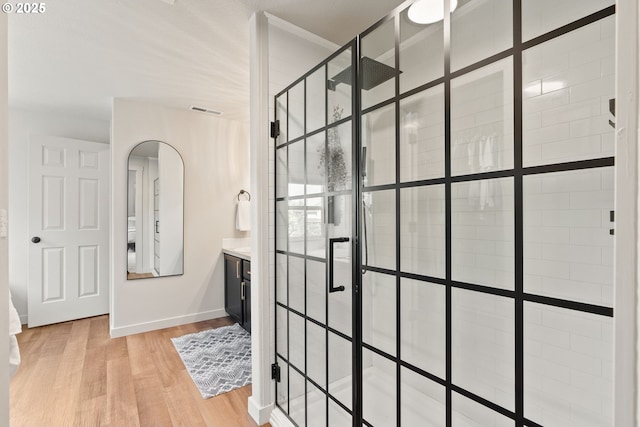 full bathroom with visible vents, a tile shower, wood finished floors, baseboards, and ornamental molding