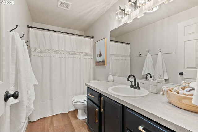 full bathroom with toilet, visible vents, wood finished floors, and vanity