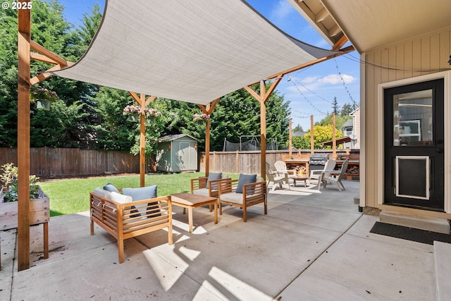 view of patio featuring a fenced backyard, an outdoor living space with a fire pit, an outbuilding, and a shed