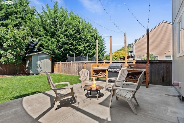 view of patio / terrace featuring an outdoor fire pit, grilling area, a shed, a fenced backyard, and an outbuilding