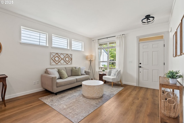 living room featuring baseboards, ornamental molding, and wood finished floors