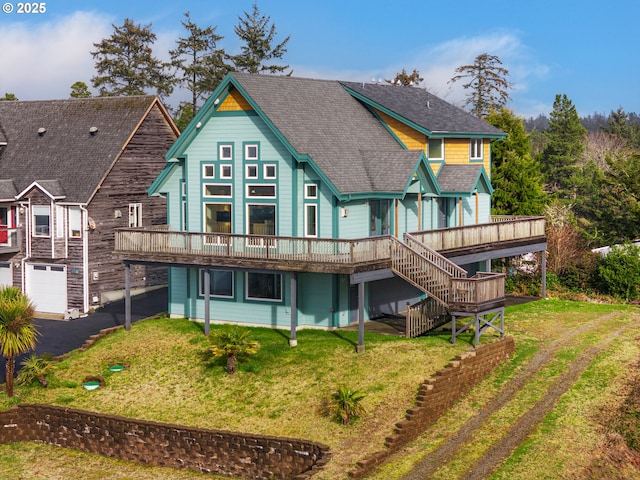 rear view of house with stairs, roof with shingles, a lawn, and a wooden deck