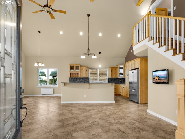 kitchen featuring dark countertops, hanging light fixtures, glass insert cabinets, a sink, and stainless steel fridge